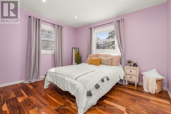 Bedroom with hardwood floors, pink walls, and a white bed - 30 Kitchen Road S Huntsville