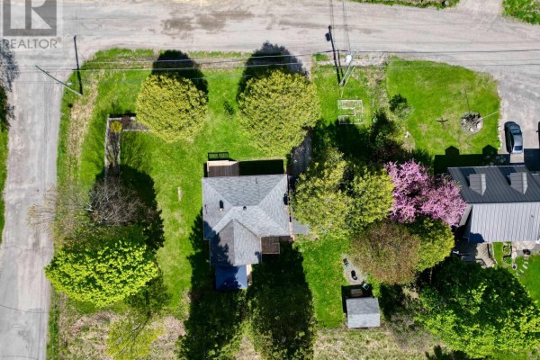 Aerial view of house with deck, trees, shed, garden beds, and fire pit - 30 Kitchen Road S Huntsville