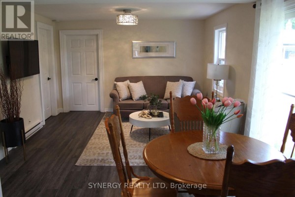 Kitchen with white cabinets, dark grey counters, white appliances, and dark wood-look flooring. - 30 Mill Lane, Strathroy Caradoc