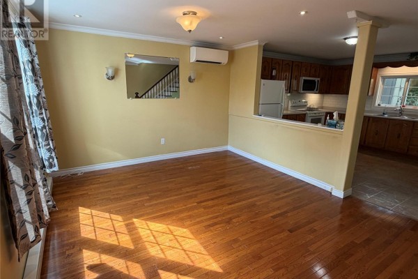 Living room with yellow walls, hardwood floors, and a view into the kitchen area. - 30 Monroe Street, St John S