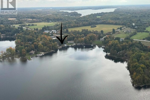 Wide aerial view of lakefront properties and surrounding landscape with a cloudy sky. - 30 R7a Road, Rideau Lakes