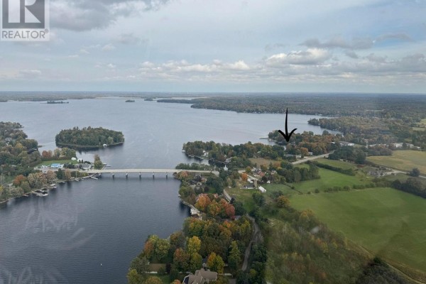 Aerial view of a landscape featuring a lake, bridge, islands, and scattered residential properties. - 30 R7a Road, Rideau Lakes