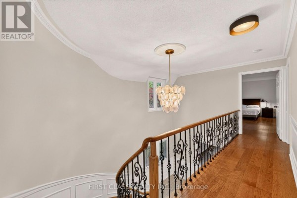 Hallway with curved staircase, ornate banister, chandelier, and hardwood floors - 30 Ritter Crescent Markham