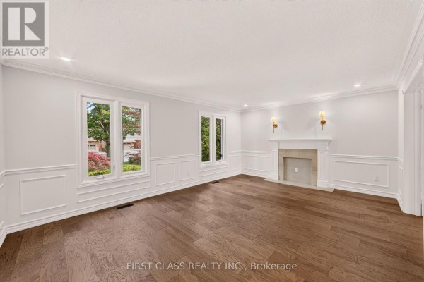 Living room with dark hardwood floors, white wainscoting, and large windows. - 30 Ritter Crescent, Markham