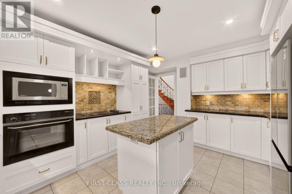 Kitchen with white cabinets, granite island, and brick tile backsplash - 30 Ritter Crescent Markham
