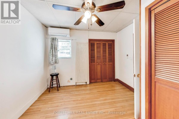 Bedroom with hardwood floors, ceiling fan, AC, and bi-fold closet doors - 30 Robert Street Toronto
