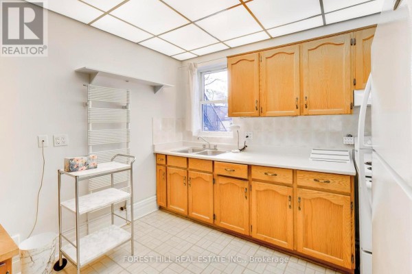 Kitchen with wooden cabinets, double sink, and white countertops - 30 Robert Street Toronto