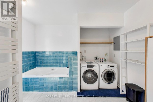 Bathtub with blue tile and washer/dryer - 30 Robert Street Toronto