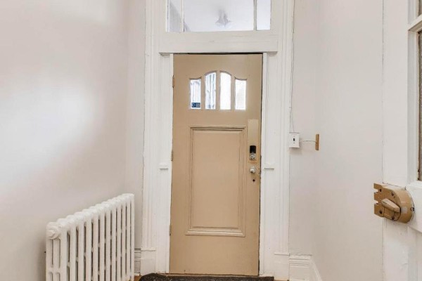Close-up of a beige interior door with glass panes and a white radiator below. - 30 Robert Street, Toronto