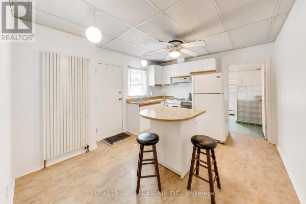 Kitchen with white cabinets, breakfast bar, and stools - 30 Robert Street Toronto