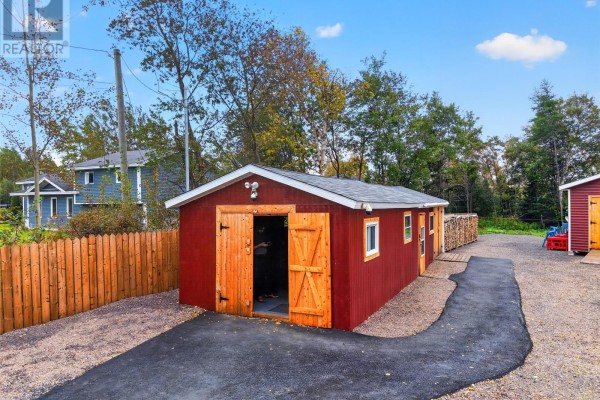 Long red garage with double wooden doors open, a paved path, and stacks of firewood beside a wooden fence. - 30 Ryder's Brook Road, Georges Brook
