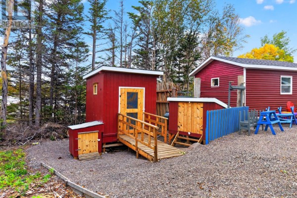 A cluster of small red and wood outbuildings with wooden ramps and stairs, surrounded by gravel and trees. - 30 Ryder's Brook Road, Georges Brook
