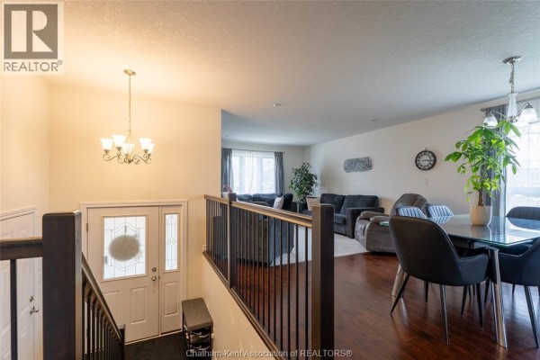 Interior view of an open-concept living and dining area with dark wood floors and a chandelier. - 30 St Michael Avenue, Chatham