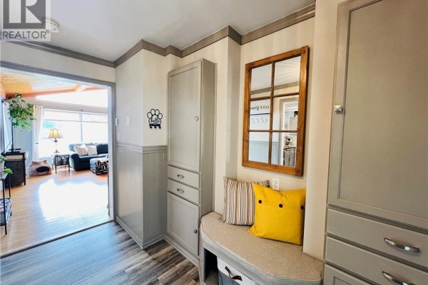 Interior entryway with grey built-in cabinets, a cushioned bench, and a window pane mirror. - 30 Stillwater Road, Digdeguash