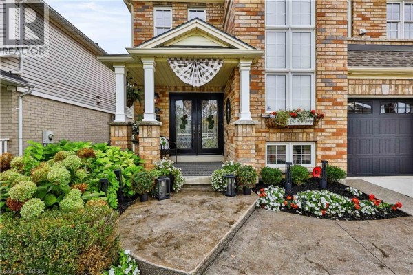Close-up view of the covered front entrance with double glass doors and decorative pillars. - 30 Waldie Crescent, Brantford