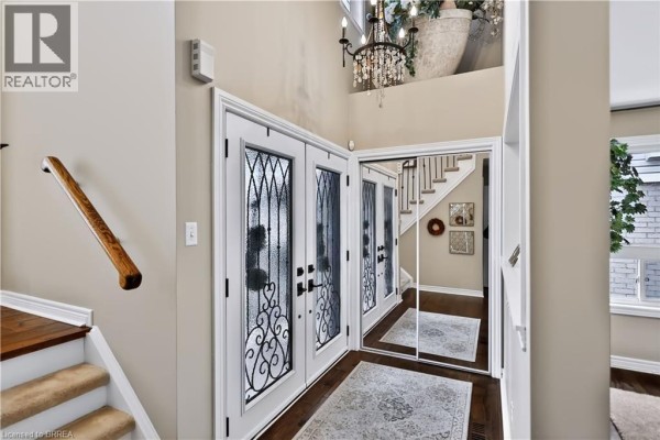 Interior view of the foyer with double glass doors, a mirrored wall, and a chandelier. - 30 Waldie Crescent, Brantford