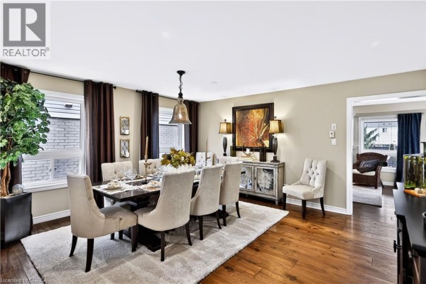 Formal dining room with a large table, upholstered chairs, a rug, and wood flooring. - 30 Waldie Crescent, Brantford
