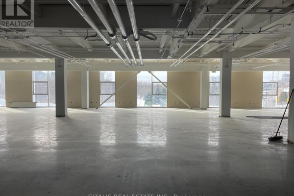 Empty commercial space with polished concrete floors and exposed ceiling pipes. - 300 - 501 Alliance Avenue, Toronto