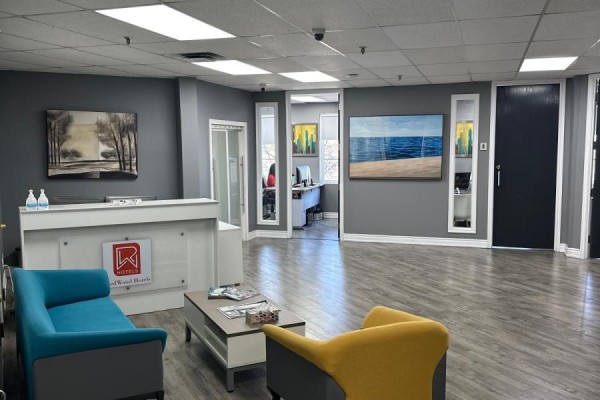 Reception area with a front desk, teal and yellow seating, and artwork on walls. - 300 - 5045 Orbitor Drive, Mississauga