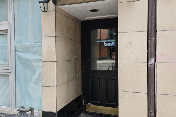 Close-up of a black paneled door with a glass insert and beige tile surround. - 300 - 524 Yonge Street, Toronto