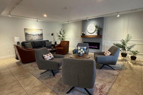 Apartment building common area with fireplace, sectional sofa, armchairs, and decorative plants. - 300 - 8 Fead Street, Orangeville