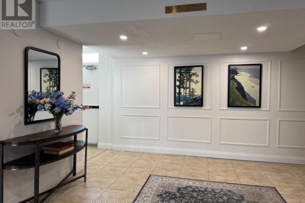 Apartment building hallway with console table, mirror, artwork, and decorative paneling. - 300 - 8 Fead Street, Orangeville