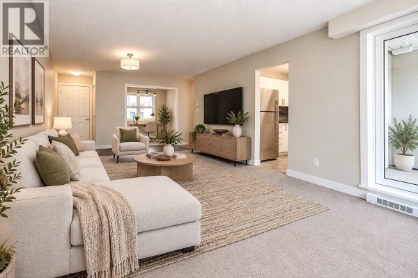 Living room and kitchen area with sofa, TV, dining chairs, and stainless steel refrigerator. - 300 2533 Penticton Street, Vancouver