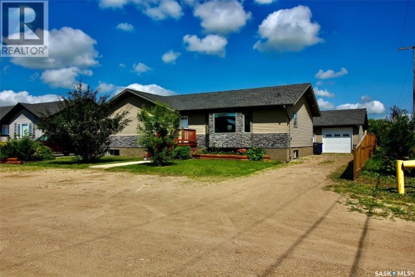View from above of a backyard featuring a wooden deck and neighboring houses and fields. - 300 7th Street, Vonda