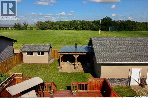 Aerial view of a fenced backyard with a shed, covered patio, and view of open fields. - 300 7th Street, Vonda