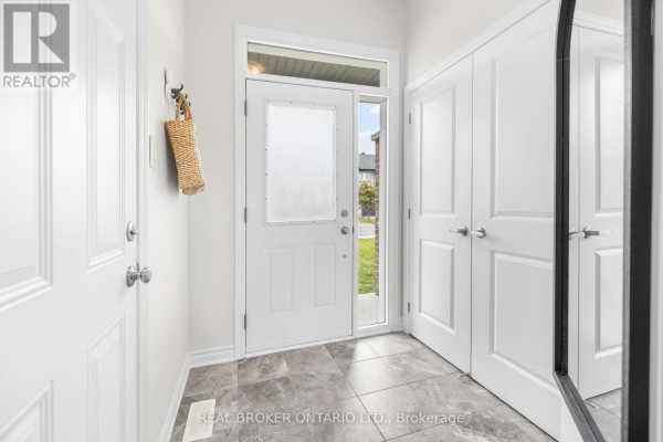 Interior entryway with white doors, coat hooks, and grey tiled flooring. - 300 Livery Street, Ottawa