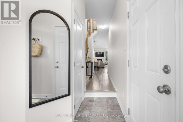 Hallway entrance with white doors, large arched mirror, and view of staircase and living room. - 300 Livery Street, Ottawa