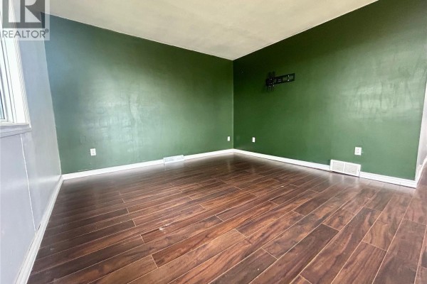Empty room with dark hardwood floors and dark green accent wall. - 300 Main Street, Lang