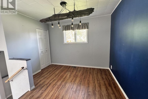 Dining area with blue and gray walls, a wooden floor, and a unique log-shaped chandelier. - 300 Martel Rd, Chapleau