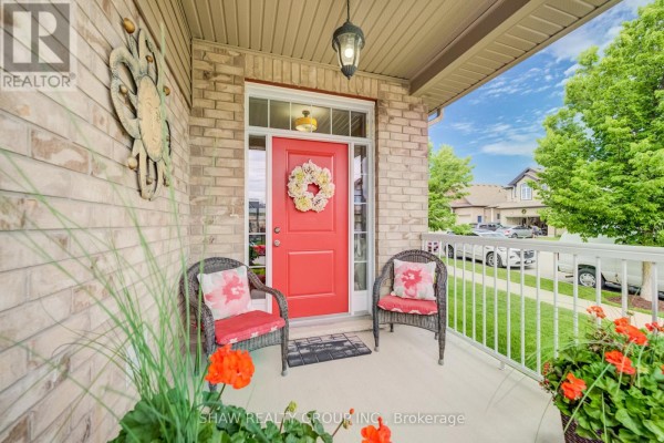 Covered front porch with two chairs, a red door, and decorative wreath. - 300 Watervale Crescent, Kitchener