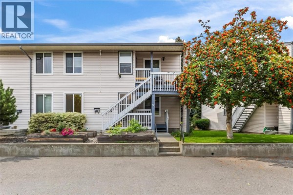 Exterior front view of a light-colored townhouse with white stairs leading to the upper level. - 3000 Richter Street Unit# 6, Kelowna