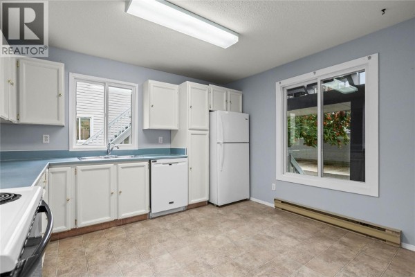 Kitchen with white cabinets, light blue countertops, sink, dishwasher, stove, refrigerator, and a window. - 3000 Richter Street Unit# 6, Kelowna