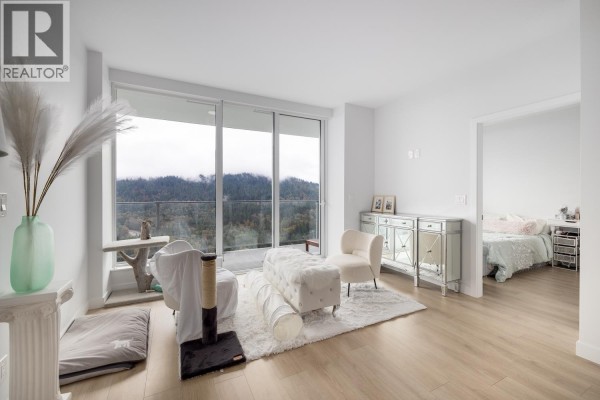 Living area featuring large windows, a cozy seating arrangement, and a view of the mountains. - 3002 567 Clarke Road, Coquitlam