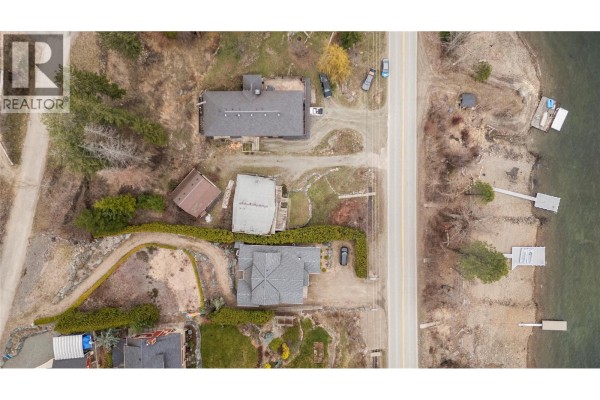 Aerial view of waterfront properties along a road, showing houses and docks. - 3003 Squilax-anglemont Road, Lee Creek