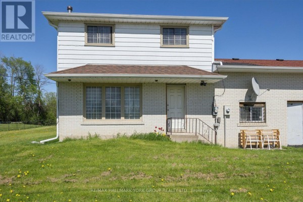 Side view of commercial building with white siding and white brick addition. - 30032 Highway 48, Georgina
