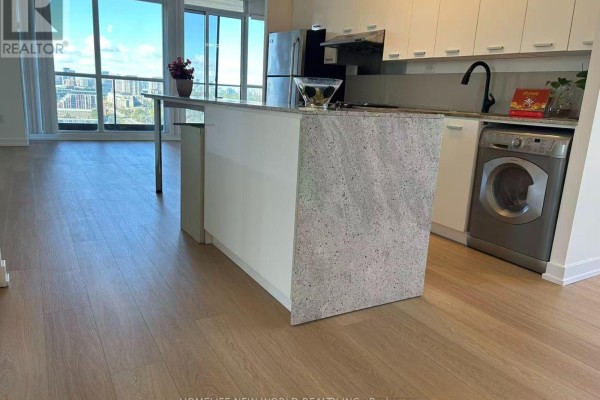 Kitchen area with granite island, stainless steel appliances, and washer. - 3005 - 33 Singer Court, Toronto