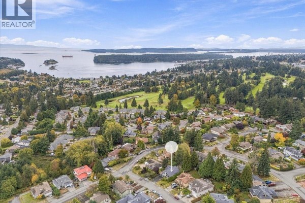 Aerial view of a suburban neighborhood with houses, a golf course, and a water tower. The property is visible. - 3005 Persimmon Pl, Nanaimo