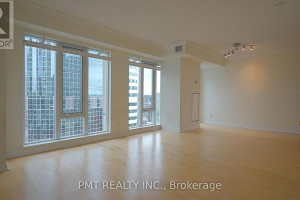 Empty living room with light wood floors, large windows, and city view. - 3008 - 210 Victoria Street, Toronto