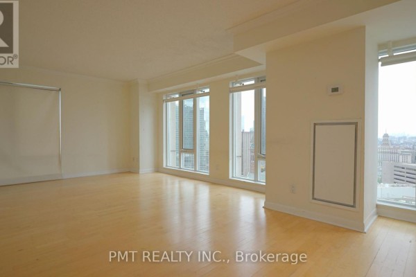 Spacious empty living room with light wood floors and city views through windows. - 3008 - 210 Victoria Street, Toronto