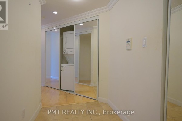 Hallway with beige walls, mirrored closet doors, and stacked washer and dryer. - 3008 - 210 Victoria Street, Toronto