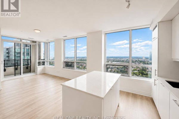 Open concept living space with a white island, large windows, and city views. - 3008 - 36 Elm Drive W, Mississauga
