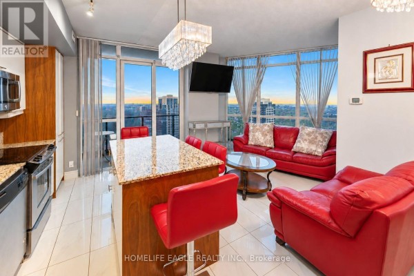 Living room with a red leather sofa, coffee table, television, and large windows with city view. - 3008 - 5 Valhalla Inn Road, Toronto