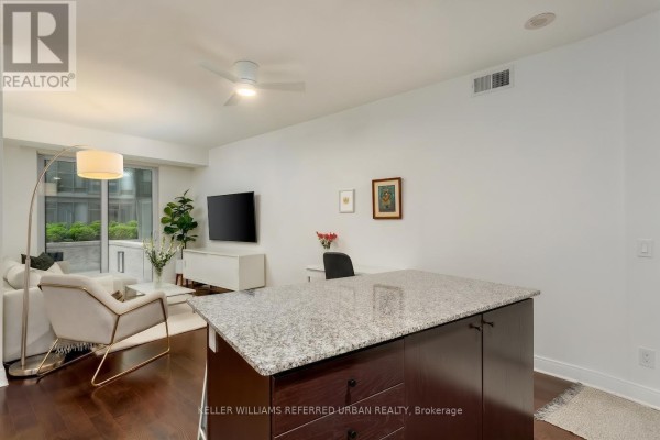 Living area with white sofa, desk, television, and view of the city from large windows. - 301 - 1 Scott Street, Toronto