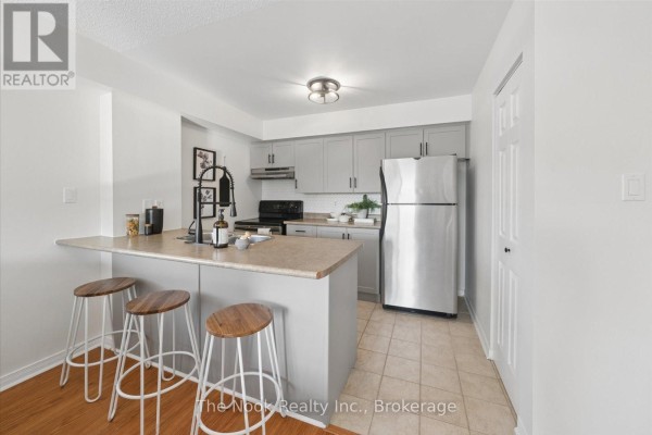 Kitchen with grey cabinets, stainless steel appliances, and an island with bar stools. - 301 - 106 Aspen Springs Drive, Clarington