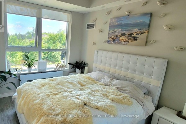 Bedroom with tufted headboard, fluffy blanket, wall art & large window - 301 - 11611 Yonge Street Richmond Hill