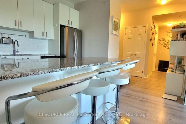 Modern kitchen with granite counters, stainless steel fridge, bar stools - 301 - 11611 Yonge Street Richmond Hill